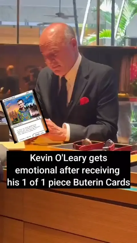 Video: Kevin O'Leary in a suit gazes down at a Buterin Card superimposed in his hands, captioned "Kevin O'Leary gets emotional after receiving his 1 of 1 piece Buterin Cards"